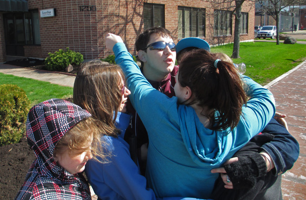 3 photos show the students gathering together into a hug that includes them all.